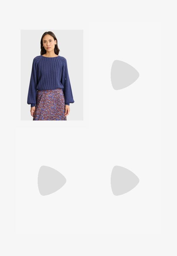 Frau in einem gestreiften navyblauen Pullover mit Ballonärmeln und einem gemusterten Rock in Lila-, Rost- und Weißtönen vor einem hellen Hintergrund.; Helle blaue weit geschnittene Jeans mit hoher Taille, die einen verblassten Look, Gesäßtaschen und einen subtilen Schlitz am unteren Ende der Beine aufweisen.; Schwarze Lederstiefeletten mit runder Zehenpartie, Schnürung vorne und einer dicken Gummisohle mit strukturiertem Profil. Mit Zugschlaufe an der Rückseite.; Blaues Denim-Tasche mit einer gepolsterten, runden Form und einem gebogenen Griff. Die Textur ist weich, mit sichtbaren Nähten und einer glatten Oberfläche.