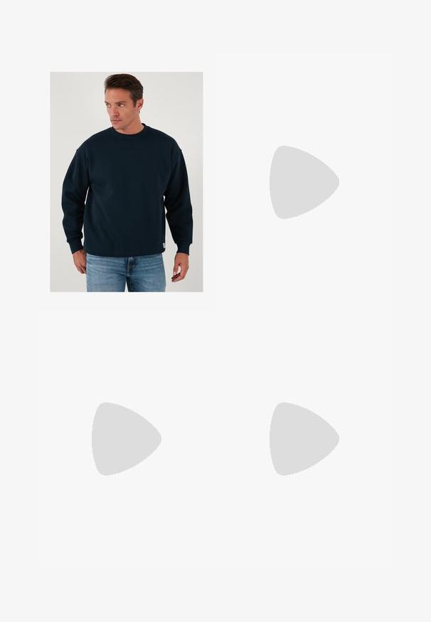 Tengerészkék környakú pulóver hosszú ujjal, laza szabású, bordázott nyakkal és mandzsettákkal, puha pamutkeverék anyagból készült.; Sötétszürke anyagból készült, bő szárú nadrág. Ráncokkal a deréknál, elegáns fazonnal és egyenes sziluettel rendelkezik.; Fekete bőr mokaszin, rojtos díszítéssel, masszív fekete talppal és sárga varrással az élén. Texturált felület.; Fekete szövet válltáska ívelt formával, egyetlen pánttal és cipzáras záródással. Puha tapintás, minimalista dizájn.