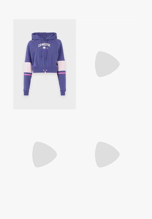 Skrajšan vijoličen pulover s kapuco in belim logotipom 'Converse All Star', kapuca s vrvicami ter kontrastne svetlo roza in temno roza črte na rokavih.; Svetlo modri jeans iz denima z sproščenim krojem, ki imajo obrabljene podrobnosti, gumbasto zapiranje z dvema gumboma in ravno krojene hlačnice.; Beli usnjeni športni čevlji s perforiranim prstnim delom, teksturiranim podplatom in belimi vezalkami, v kombinaciji s širokimi rdečimi hlačami in modro-rumeno ozadje.; Zlate uhane v obliki obročkov z gladko, sijočo površino. Krožna zasnova s majhnim nosilcem in prozornim podplatom za varno nošenje.