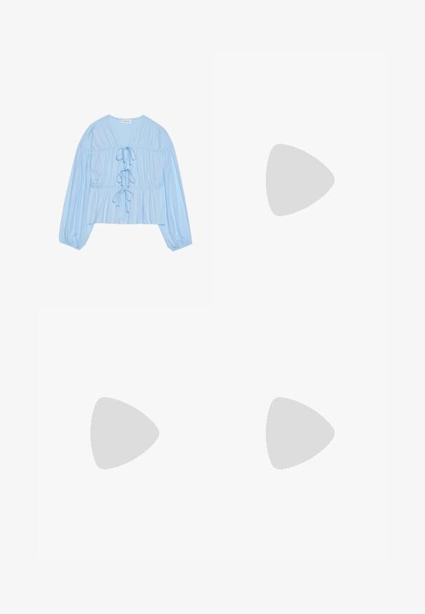 Débardeur de sport blanc sans manches avec bordures bleu marine et accents rouges. Il présente un col rond et un logo Fila sur la poitrine. Tissu lisse et léger.; Blouse à manches longues bleu clair en tissu doux, avec un col en V, des détails à cordon de serrage et une taille froncée pour un fit décontracté.; Jeans en denim blanc avec un design à jambe droite, style cinq poches et accents en métal cuivré. Finition effilochée au niveau des chevilles.; Baskets en daim marron avec des accents et des lacets blancs. Semelle en caoutchouc gomme. Portées avec des chaussettes blanches à rayures noires. Sol texturé vert.