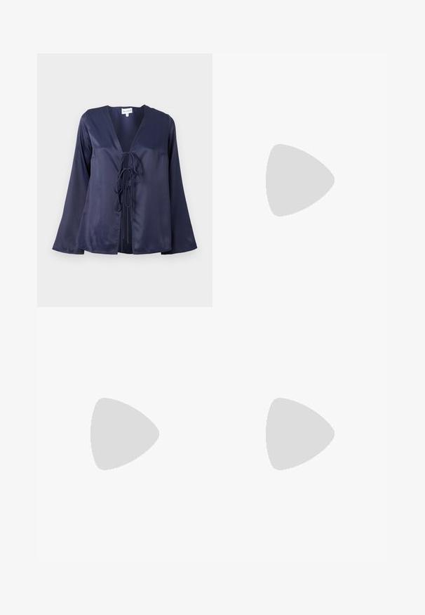 Blusa de satén azul marino con escote en V, mangas largas acampanadas y cierre de lazo en la parte delantera. Textura suave con un diseño sencillo y elegante.; Pantalones blancos de pierna recta hechos de una tela ligera. Presentan una parte frontal plana, presillas para el cinturón y sin patrones o decoraciones visibles.; Stuart Weitzman NUDIST BLOCK 75 - Sandalias tobilleras - white; Bolso de mano de cuero sintético azul marino con logotipo dorado, cierre de cremallera y tira de hombro ajustable, con una textura suave y forma rectangular.