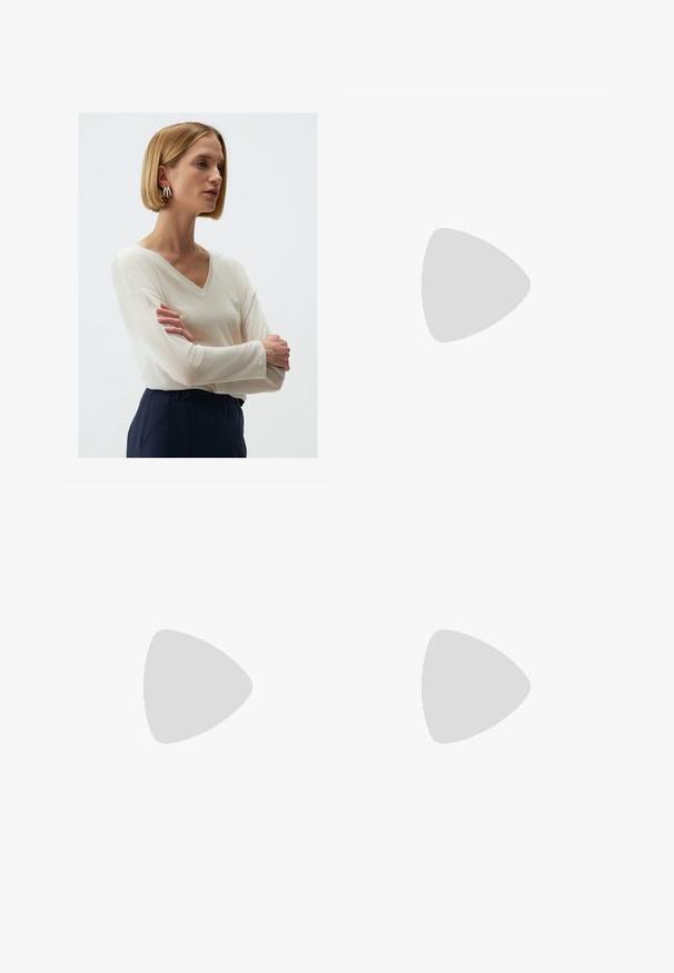 V-hals lange mouwen top in lichtgewicht, doorschijnende crèmewitte stof. Gecombineerd met donkerblauwe broek. Model heeft een kort kapsel en zilveren oorringen.; Witte wijde jeans van denim met een hoge taille, voorzien van vijf zakken en metalen hardwareaccenten. Gladde textuur, geen zichtbare patronen.; Blauwe suède schoenen met roze strepen en witte veters, voorzien van een gumrubberen zool, gecombineerd met losse denim broek op een groene ondergrond.; Geweven straw handtas in beige met een gebogen vorm, een kort handvat en een zijrits. Beschikt over een gestructureerd oppervlak en een minimalistisch ontwerp.