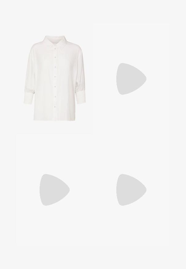 Witte blouse met klassieke kraag, korte pofmouwen en gerimpelde manchetten. Gemaakt van lichte stof met een gladde textuur.; Crème-kleurige satijnen wijde broek met zwarte geborduurde geometrische patronen langs de zoom. Beschikt over een gladde textuur en een gekleed silhouet.; Beige leren blokhakpumps met een spitse neus, zwarte trim langs de opening en een dunne verstelbare slingbackriem met gouden hardware.; Lederen handtas met een bruine afwerking, voorzien van een beige gemerkt stoffen paneel, gouden hardwaresluiting en een verstelbare schouderriem.
