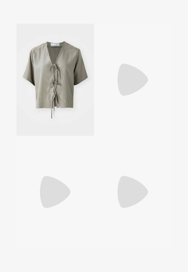Blusa verde oliva a maniche corte con scollatura a V e legature frontali. Realizzata in tessuto liscio con cuciture minime e una vestibilità comoda.; Jeans a gamba larga in denim blu scuro. Presentano cinque tasche, passanti per cintura e un orlo grezzo in fondo con dettagli di cucitura visibili.; Sandali con tacco in vernice nera, con punta squadrata, cinturini alla caviglia e fibbie in argento. Presentano un tacco a blocco spesso per maggiore stabilità.; Borsa tote in pelle nera con texture liscia, forma rettangolare e due manici lunghi. Nessun hardware o decorazione visibile.