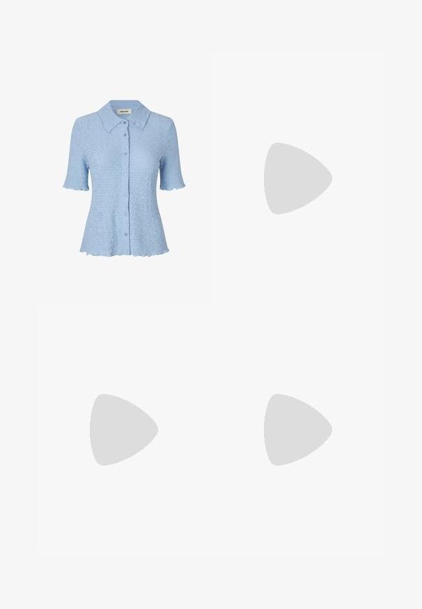 Camisa de manga curta azul clara com um padrão ondulado texturizado, fecho de botão e bordas das bainhas e mangas em forma de onda. Design com colarinho.; Anna Field Calças - dark blue; Sandal de pele preta com bico pontiagudo e um salto bloco baixo. Apresenta uma tira no tornozelo com uma fivela em tom dourado. Textura suave.; Bolsa preta com forma estruturada, textura suave e um fecho metálico. Combinada com calças largas pretas e sandálias de salto aberto sobre um chão de madeira.