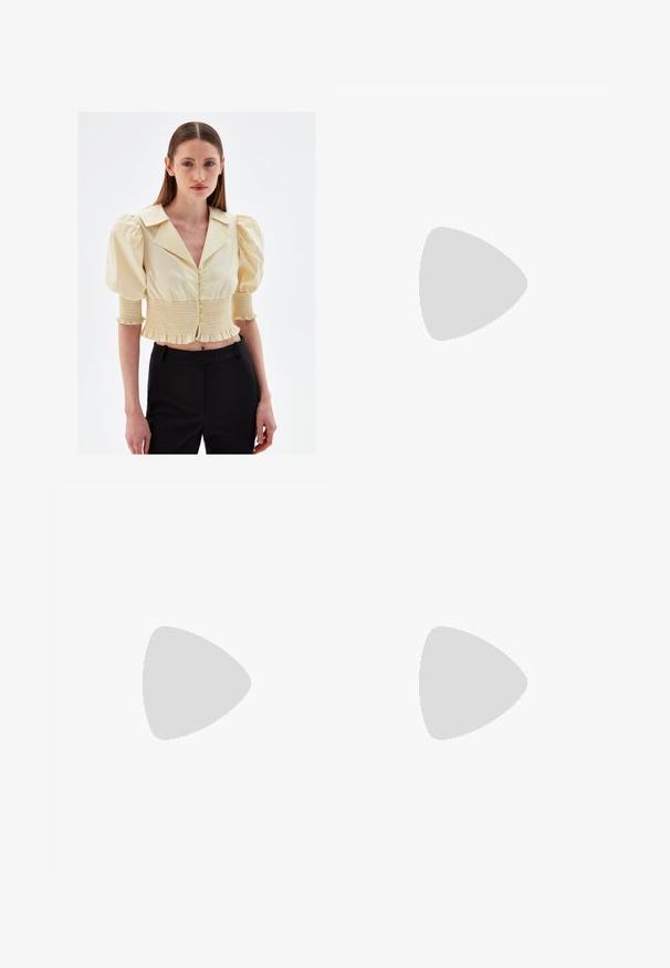 adL SHORT SLEEVE GIMPED - Hemdbluse - yellow; Weiße, ausgestellte Jeans aus einem glatten Baumwollstoff, mit fünf Taschen, einem Metallknopfverschluss und Gürtelschlaufen. Die Beine haben ein leichtes Verfeinerungsdetail.; Beige Slingback-Schuh mit schwarzer Kappe, quadratischem Absatz und zwei Riemenakzenten, aus glattem Material gefertigt.; Weiße Kunstleder-Handtasche mit umklappbarem Deckel, goldfarbener Hardware und abnehmbarem Schultergurt. Verfügt über einen Schnallenverschluss und eine glatte Textur.