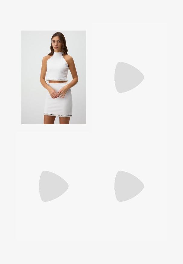 Witte twee-delige outfit met een haltertop en een bijpassende mini-jurk. Beide hebben een glanzende kristallen accent langs de zoom.; Zwarte wijde pantalon gemaakt van een soepele stof, met een aansluitende tailleband en subtiele plooien aan de voorkant voor extra textuur.; Zwarte leren sandaal met twee brede banden over de voet, een vierkante neus en een lage blokhak. Glad textuur en minimaal ontwerp.; Zwarte handtas met gestructureerde vorm, gladde textuur en een metalen sluiting. Gecombineerd met brede zwarte broeken en sandalen met open teen op een houten vloer.