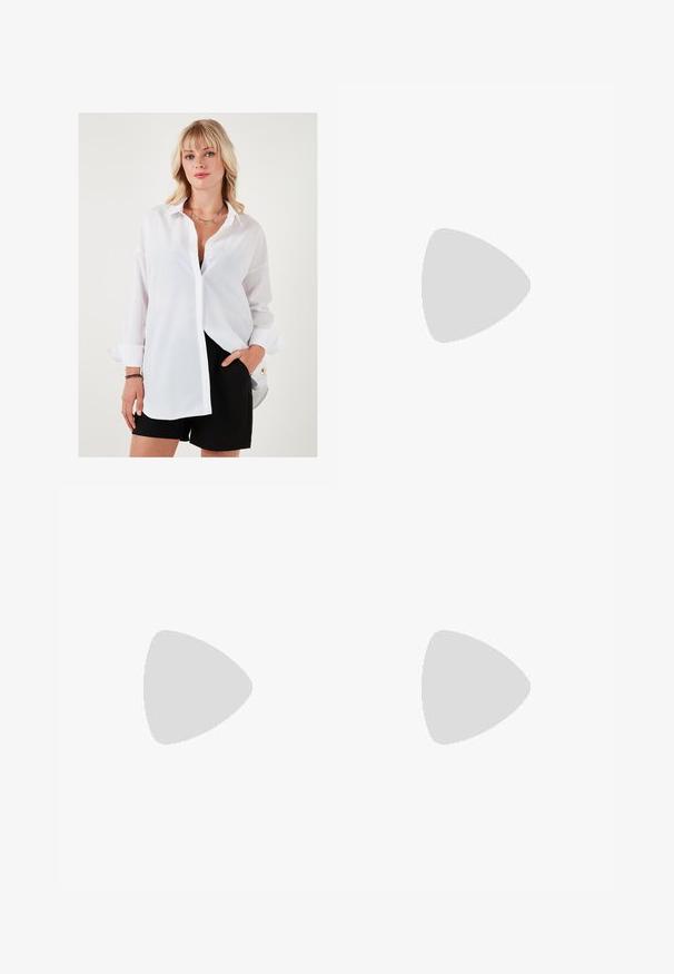 Witte overhemd met lange mouwen, losse pasvorm en een scherpe kraag. Gecombineerd met zwarte shorts met een gouden accentknop.; Zwarte wijde broek met hoge taille, knoopdetails op de tailleband en plooien aan de voorkant.; Zwarte lederen instappers met een platte hak, met een decoratieve gouden hardware detail aan de voorkant en een gladde textuur.; Bruine leren schoudertas met een slonzig ontwerp, gouden hardware en contrasterende witte stiksels, vastgehouden door een persoon in denim kleding.