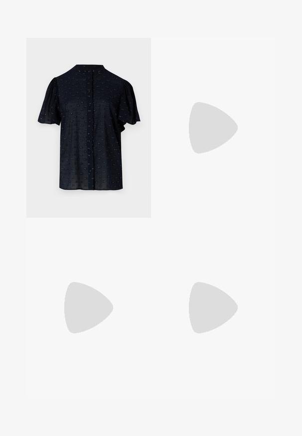 Blusa navy a maniche corte con maniche a sbuffo, scollatura rotonda, chiusura con bottoni e motivo testurizzato con piccoli dettagli ricamati.; Pantaloni in un tessuto satin beige chiaro con una texture liscia, caratterizzati da una vita alta, gambe larghe e pieghe sottili per un tocco di dettaglio.; Pump in pelle nera con punta affusolata e tacco basso a blocco. Presenta una cinghia alla caviglia con una fibbia in tonalità oro. Texture liscia.; Borsa nera con forma strutturata, texture liscia e una chiusura metallica. Abbinata a pantaloni neri larghi e sandali open-toe su un pavimento in legno.