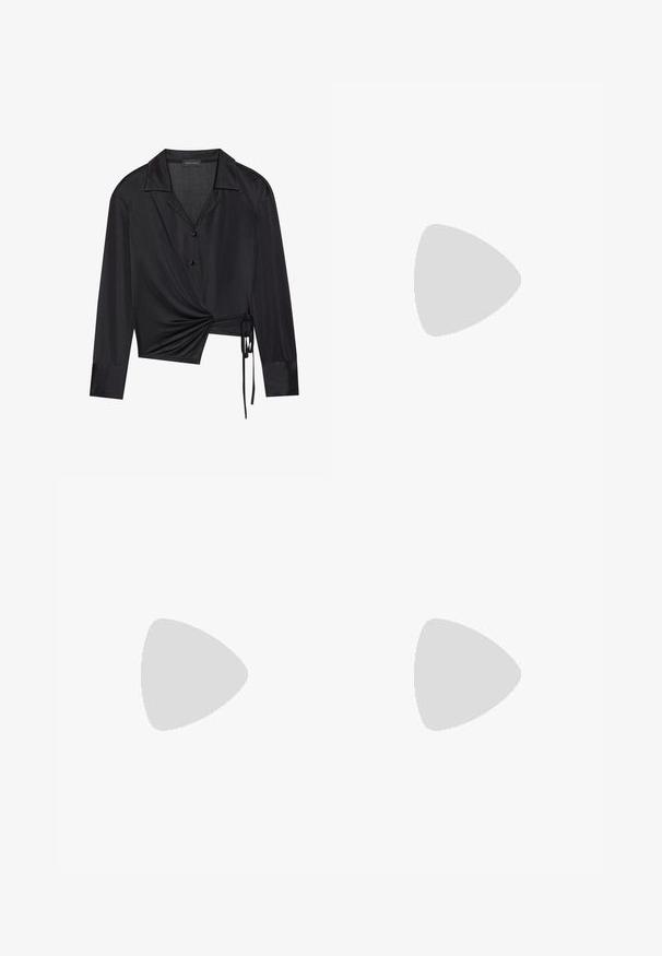 Blusa preta envolvente com mangas longas, gola clássica e detalhe de torção na frente. Feita de um tecido suave com uma textura ligeiramente transparente.; Calças pretas ajustadas, feitas de um tecido suave, com perna reta, pregas frontais e fecho de botão na cintura.; Mocassim de couro envernizado preto com um salto baixo, apresentando uma tira e um detalhe em dourado na parte superior, textura suave e ponta arredondada.; Bolsa preta com forma estruturada, textura suave e um fecho metálico. Combinada com calças largas pretas e sandálias de salto aberto sobre um chão de madeira.