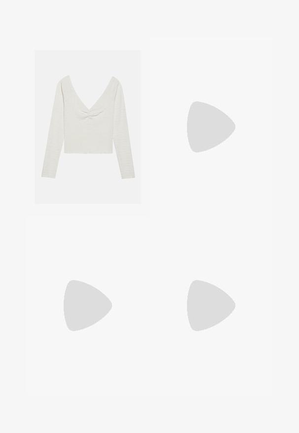 Maglietta a maniche lunghe color avorio con scollatura a V profonda e dettaglio annodato sul davanti, realizzata in tessuto texturizzato e con orlo corto.; Pantaloni cargo grigio chiaro con elastico in vita, lacci regolabili, multi tasche laterali e orli con zip. Realizzati in tessuto morbido e leggero.; Scarpe da ginnastica bianche e grigie realizzate in materiali scamosciati e in pelle. Presentano una suola in gomma e un design con lacci, accentuato da un dettaglio scuro sul tallone.; Borsa a tracolla nera in suede con design curvo, caratterizzata da dettagli in rivetti e superficie testurizzata. Tracolla regolabile con dettagli a borchia lungo il bordo.
