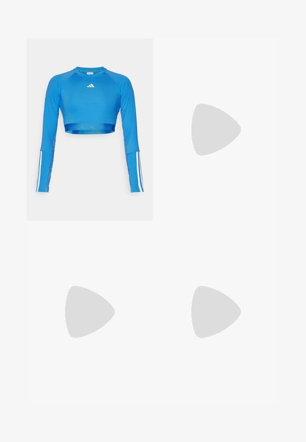 Top sportivo cropped a maniche lunghe di colore blu, realizzato in un materiale liscio e caratterizzato da accenti di strisce bianche sulle maniche e un piccolo logo sul petto.; Leggings blu in materiale elasticizzato. Presentano un ampio elastico in vita con dettagli del logo e inserti in mesh lungo le gambe per la ventilazione.; Scarpe bianche flat con bordi e suola nera, abbinate a calze a coste di un delicato viola chiaro con fasce bianche incrociate. Ambientate su uno sfondo verde.; Occhiali da sole neri con una forma cat-eye elegante, dotati di lenti sfumate e con il nome del marchio "vogue" stampato sul lato.