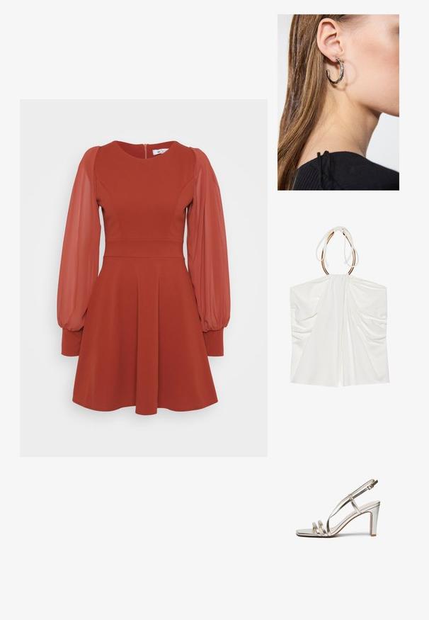 Top branco sem mangas com tecido drapeado, pescoço halter ajustado e detalhes em metal dourado. Textura suave e design leve e fluido.; Vestido vermelho com mangas curtas volumosas em tule, corpete ajustado, saia ampla e fecho nas costas. Feito de um tecido texturizado com um acabamento suave.; Sandal de salto alto prateado metálico com biqueira aberta, apresentando três tiras finas sobre o pé e uma tira no tornozelo com fivela.; Bolsa de mão metálica dourada com uma textura suave, apresentando um fecho em aba triangular. A mão que a segura tem unhas bem cuidadas.; Brinco de argola prateada com acabamento polido, apresentando pequenos detalhes em dourado e uma forma redonda, usado na orelha.