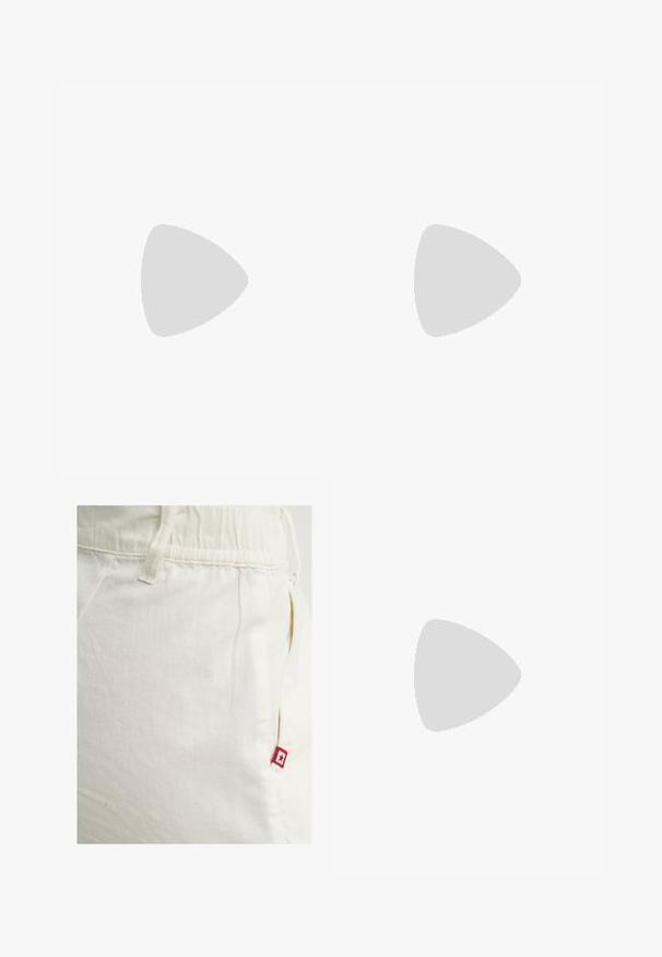 Haut blanc à manches courtes avec un motif texturé en côtelé et un col rond. Fabriqué dans un matériau doux. Longueur cropped.; Un pantalon de survêtement couleur crème avec une taille élastique et une poche latérale, arborant une petite étiquette de logo rouge avec une étoile sur la poche droite.; Baskets avec une tige en cuir blanc, un bout en daim gris et trois bandes noires. Présente un logo bleu sur la languette et une semelle en caoutchouc texturée.; Lunettes de soleil en écaille marron avec des verres ovales et une teinte gris foncé. Présente un accent en ton doré sur les branches. Texture en plastique lisse.; Sac en cuir marron avec une finition texturée et des accessoires en argent, tenu à la main à côté d'une jupe en cuir marron et d'un pull à motifs.