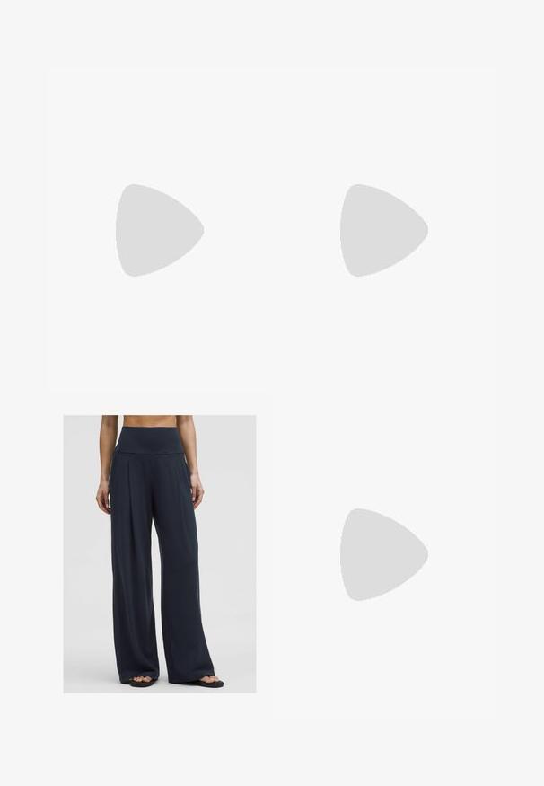 Top nero senza maniche con scollatura a V profonda, realizzato in tessuto morbido. Design semplice senza motivi o decorazioni.; Una donna sta in piedi indossando pantaloni ampi a vita alta di colore scuro abbinati a sandali, mostrando uno stile comodo e casual.; Infradito con tacco marroni, dotati di una fascia sottile e un puntale arrotondato, con un piccolo dettaglio dorato sulla soletta.; Occhiali da sole ovali marroni con lenti scure. La montatura è realizzata in un materiale marrone trasparente e presenta un logo stampato sulle tempie.; Borsa tote beige intrecciata con un design morbido e una sola tracolla. Presenta un motivo Texturizzato su tutta la superficie.