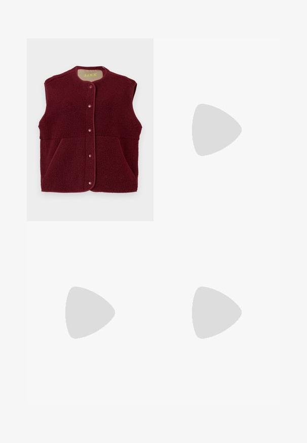 Burgundi színű ujjatlan polár mellény, elöl patentgombokkal és két elülső zsebbel, kerek nyakkivágással.; Fehér, sima pamutből készült gombos ing, klasszikus gallérral, hosszú ujjakkal és ívelt hemvéggel. A gombok kicsik és fehérek.; Fekete, sima anyagból készült testre szabott nadrág, közepes derekú, elől pleat-elt és egyenes szabású.; Burgundi lakkbőr balettcipő kerek orral, elöl kis masni díszítéssel és alacsony, fekete gumi talppal. Simára csiszolt felület.