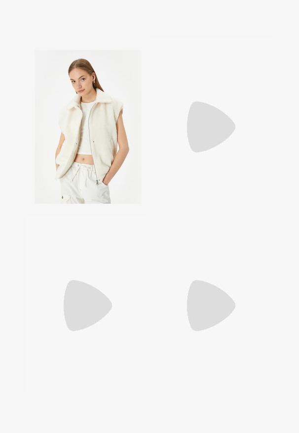 Fleece-Weste in Off-White mit Reißverschluss, Kragen und ärmellosem Design. Weiche Textur, ausgestattet mit zwei Seitentaschen.; Rotes langärmeliges Baumwolloberteil mit gerippter Textur und rundem Ausschnitt. Mit einem weißen Logo auf der Brust. Cropped-Design.; Graue Baumwollhose mit wolkenartigem Muster, weit geschnittenem Design und Taschen vorne. Der Stoff ist glatt mit einer leicht strukturierten Oberfläche.; Graue Turnschuhe aus Mesh-Material mit weißen Akzenten, kombiniert mit blauen Jeans, die an den Knöcheln umgeschlagen sind.; Beige Handtasche aus Kunstfell mit plüschiger Textur, runden Oberhandgriffen, abnehmbarem Schulterriemen und einem dreieckigen dekorativen Anhänger.